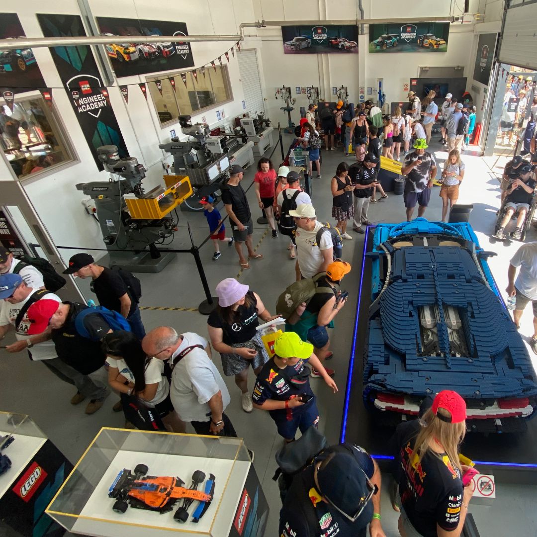 A crowd of people looking at lego models of cars